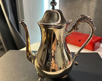 Ornate silver-plated coffee pot with clawed feet and decorative handle