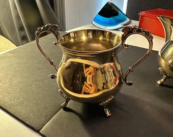 Vintage silver-plated creamer with scrolled handles and feet