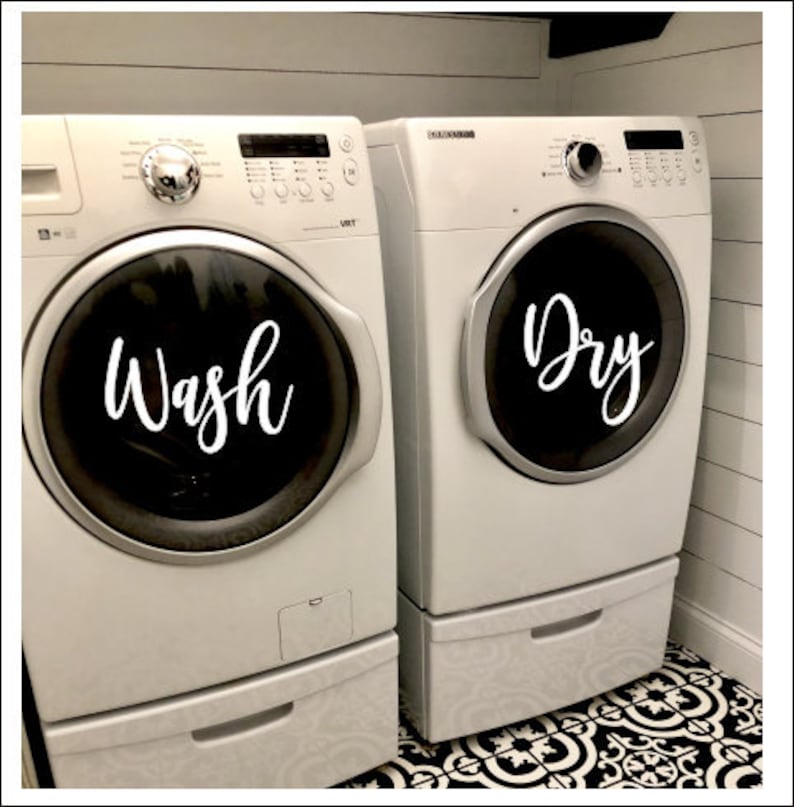 Puede incluir: Dos lavadoras blancas, una con la inscripci&oacute;n "Wash" y la otra "Dry". Las m&aacute;quinas tienen puertas circulares negras y est&aacute;n sobre un suelo con estampado en blanco y negro. Las paredes son blancas.