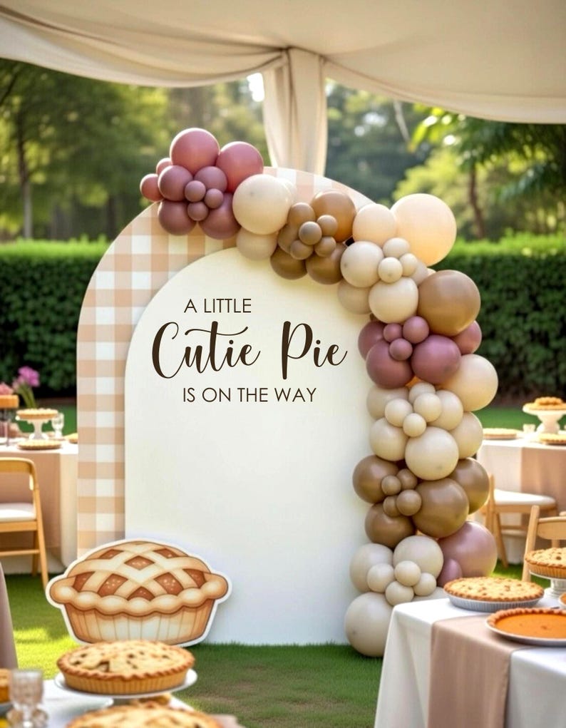 May include: An arched backdrop with a beige and white gingham border and a white center panel featuring the text A LITTLE Cutie Pie IS ON THE WAY. A cluster of balloons in shades of cream, tan, and mauve frames the arch, with a pie illustration.