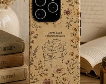 Könnte beinhalten: Eine beige Smartphone-Hülle mit einem zarten Blumenmuster in Braun-, Gelb- und Rosatönen. In der Mitte befindet sich eine Strichzeichnung eines Bücherstapels mit dem darüber gedruckten Text I have lived a thousand lives.