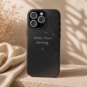 K&ouml;nnte beinhalten: Schwarze Handyh&uuml;lle mit Sternennacht-Design. Die H&uuml;lle zeigt den Text "Hello, Feyre darling." in handschriftlichem Stil. Unter dem Text befindet sich ein kleiner Halbmond. Die Handyh&uuml;lle hat ein Kameramodul mit drei Objektiven.