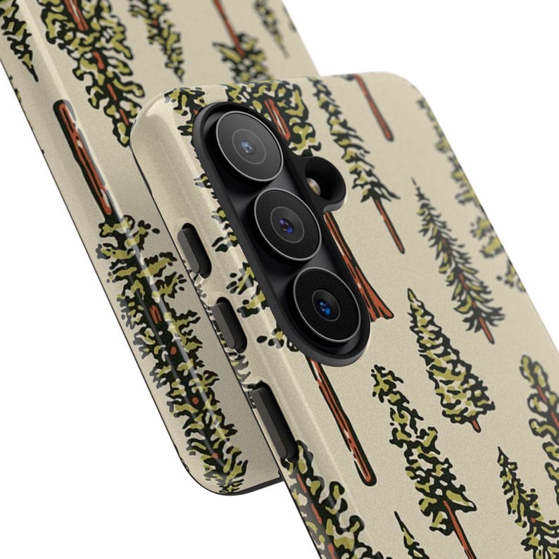 May include: A phone case with a repeating pattern of stylized evergreen trees in shades of green and brown on a cream background. The case has a black camera module with three lenses and a flash. The design is repeated on the second case.