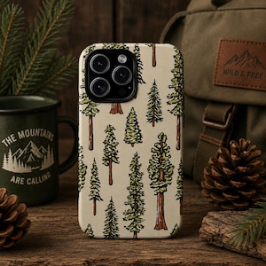 Könnte beinhalten: Eine Handyhülle mit einem sich wiederholenden Muster aus grünen und braunen Bäumen auf beigem Hintergrund. Daneben eine grüne Tasse mit dem Text "THE MOUNTAINS ARE CALLING" und ein Rucksack mit einem "WILD & FREE" Aufnäher.