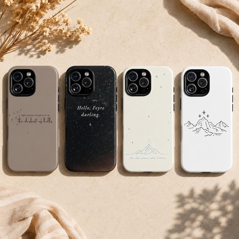 K&ouml;nnte beinhalten: Vier Telefonh&uuml;llen in einer Reihe, jede mit einem anderen Design. Die erste ist taupefarben mit Text, die zweite ist schwarz mit Text, die dritte ist cremefarben mit einem Bergmotiv und die vierte ist wei&szlig; mit einem Bergmotiv.