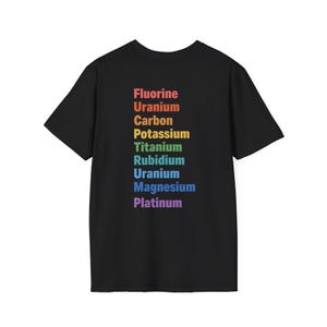 May include: A black short-sleeved t-shirt featuring a vertical list of chemical elements printed in a rainbow gradient. The text reads Fluorine, Uranium, Carbon, Potassium, Titanium, Rubidium, Uranium, Magnesium, and Platinum in descending order.