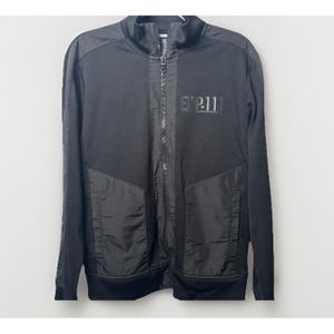 May include: Black zip-up jacket with the text "EXP-11" on the chest. The jacket features a stand-up collar, a full-length zipper, and perforated panels on the front. The jacket is made of a smooth, matte fabric.