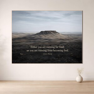 Peut inclure: Une impression murale rectangulaire représentant un paysage de mesa au sommet plat sous un ciel nuageux. Le texte indique : Either you are running for food; or you are running from becoming food. — Jensen Huang. L'impression a un cadre fin.
