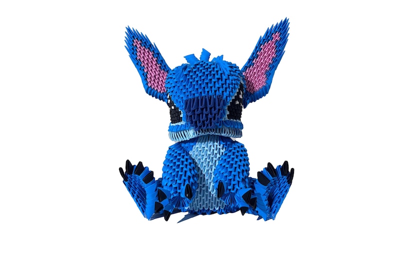 May include: A blue origami figure of a cartoon character with large ears and black eyes. The figure is sitting with its arms and legs outstretched. The ears have pink interiors, and the feet have black claws. The figure is made of many small, folded paper pieces.