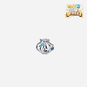 May include: A silver seashell charm with two blue accents. The charm has an open design with curved lines, and two small, round blue stones. The charm is likely for a bracelet or necklace.