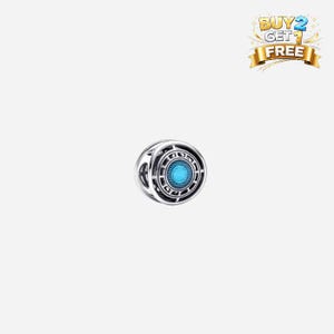 Puede incluir: Un charm plateado con un diseño circular y un centro azul brillante. El charm tiene un patrón geométrico detallado y una estética futurista. Es probable que sea un colgante o una cuenta para una pulsera o collar.