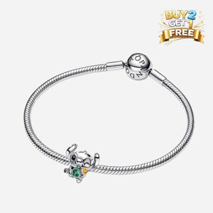 May include: A silver bracelet with a charm featuring the character Stitch from Lilo & Stitch. The charm is colorful with green, pink, and yellow accents. The bracelet has a snake chain design and a round clasp. The image also includes a "BUY 2 GET 1 FREE" banner.