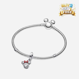 K&ouml;nnte beinhalten: Ein silbernes Armband mit einem Mickey Mouse-Kopfverschluss und einem Minnie Mouse-Charm. Der Charm hat eine rote Schleife und klare Steine. Das Armband befindet sich auf wei&szlig;em Hintergrund. Das Bild enth&auml;lt auch den Text "BUY 2 GET 1 FREE".