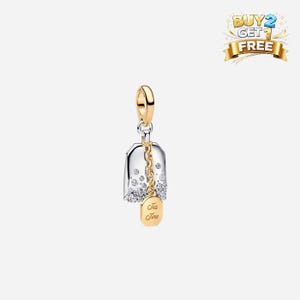 Könnte beinhalten: Ein gold-silberner Charm mit einem Teebeutel-Design. Der Charm hat eine transparente, glockenförmige Oberseite mit eingebetteten Kristallen und eine goldene Kette. Ein goldener Anhänger unten zeigt "Tea Time".