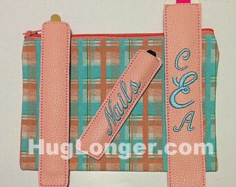 May include: Three pink fabric pouches with different embroidery. The pouches are on a plaid fabric background. The pouches are labeled "Nails", "C & A" and one is blank.