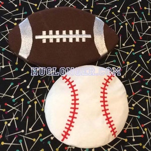 May include: A brown and white football and a white baseball with red stitching. The balls are on a black background with colorful pins.
