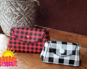 May include: Two small purses with a checkered pattern. One purse is red and black with a red heart-shaped button. The other purse is white and black with a white button.