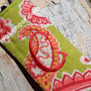 May include: A green and pink paisley patterned fabric eyeglasses case with a red embroidered letter C.