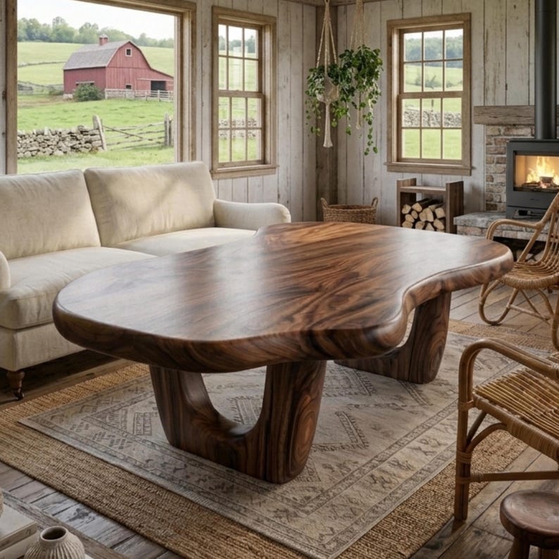 Puede incluir: Una gran mesa de centro de madera de forma org&aacute;nica, con un rico acabado marr&oacute;n oscuro. La mesa tiene un dise&ntilde;o &uacute;nico y fluido y se apoya en dos patas curvas y robustas. La mesa es el punto focal de un sal&oacute;n acogedor.