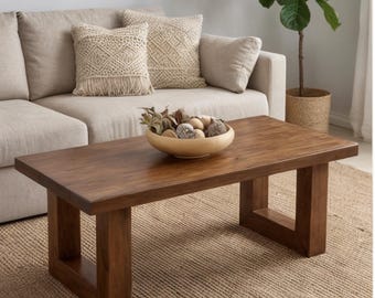 May include: A rectangular coffee table made of dark brown wood with a thick, solid top and two sturdy, U-shaped legs. A light-colored wooden bowl filled with various dried decorative spheres and natural elements sits centered on the table surface.