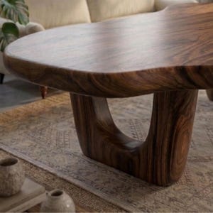 Puede incluir: Una mesa de centro de madera maciza marr&oacute;n oscuro con una forma org&aacute;nica &uacute;nica. La tapa tiene un borde liso y curvado y descansa sobre una sola base escultural. La base tiene un dise&ntilde;o abierto distintivo. La mesa es una pieza destacada para una sala de estar.