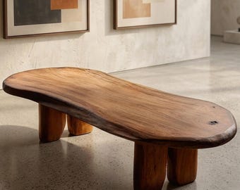 May include: A solid wood bench with a natural edge and three pairs of rounded legs. The bench is a warm brown color and has a smooth, polished surface. The design is modern and minimalist.