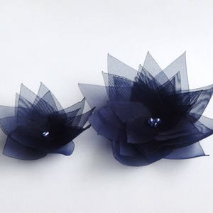 May include: Two navy blue tulle flower embellishments with a single rhinestone in the center of each flower.