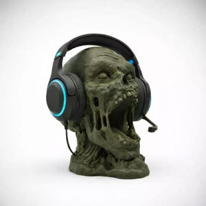 May include: A green zombie head-shaped headphone stand with a black headset. The headset features blue accent lights on the earcups and a microphone. The stand is a detailed sculpture of a zombie head with an open mouth.