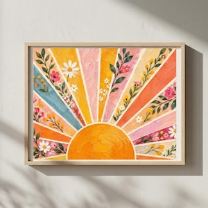 May include: A rectangular wall art print in a light wood frame featuring a textured oil painting of a rising sun. The sun is a solid orange semicircle at the bottom, with radiating beams in shades of yellow, pink, orange, and blue, each decorated with painted green vines and small white, yellow, and pink flowers.