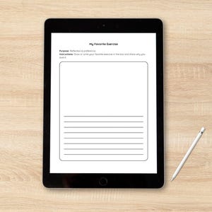 Puede incluir: Una tableta negra que muestra una hoja de trabajo "Mi ejercicio favorito" con instrucciones y l&iacute;neas para escribir. Un l&aacute;piz &oacute;ptico blanco descansa sobre una superficie de grano de madera clara.