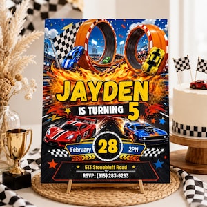 May include: A rectangular birthday party invitation sign featuring a race car theme with orange loop tracks, a checkered flag, and flames. The text reads: JAYDEN IS TURNING 5, February 28, 2PM, 513 Stonebluff Road, and RSVP: (915) 283-8283.