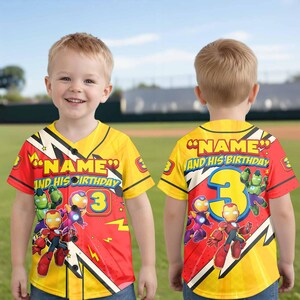 Puede incluir: Una camiseta de b&eacute;isbol amarilla y roja con el texto "NAME AND HIS BIRTHDAY" y el n&uacute;mero "3". La camiseta presenta ilustraciones de dibujos animados de superh&eacute;roes. La camiseta la lleva un ni&ntilde;o peque&ntilde;o.