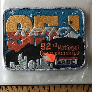 May include: A blue, orange, and white embroidered patch with the text "Reno 92nd National Championships" and the logo "ABC".
