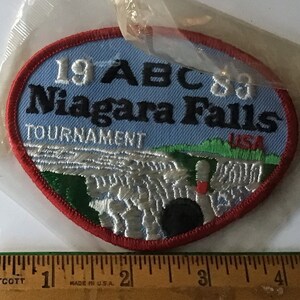 May include: A blue and red embroidered patch with the text "19 ABC 88 Niagara Falls Tournament USA" and a depiction of Niagara Falls.