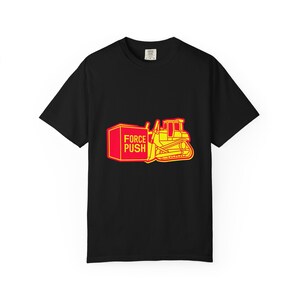 May include: Black t-shirt featuring a yellow and red graphic of a bulldozer pushing a red box. The box has the words "FORCE PUSH" printed on it. The design is outlined in yellow.