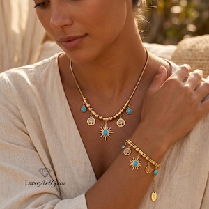 Puede incluir: Juego de collar y pulsera dorados con detalles turquesa y colgantes con encantos. El collar tiene un colgante de sol y amuletos de árbol de la vida. La pulsera tiene amuletos similares.