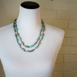 May include: A double strand necklace with turquoise oval beads on a brown cord.