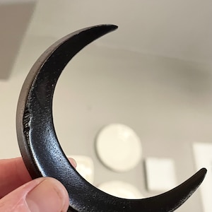 May include: A black crescent moon shaped wall decor made of metal.