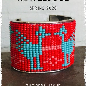 Op de afbeelding: Een rode, zilveren en turquoise kralenarmband met een geometrisch patroon. De armband is gemaakt van kleine kralen en heeft een zilveren metalen band. De armband is een statement piece en zou een geweldige toevoeging zijn aan elke outfit. De tekst "TRAVELOGUE SPRING 2020 THE PERU ISSUE" is afgedrukt op de afbeelding.