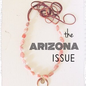 Puede incluir: Una portada de revista con el título "TRAVELOGUE" y el texto "the ARIZONA ISSUE" en letras negras y en negrita. La portada presenta un collar de cuentas rosas y blancas con un colgante de media luna. El texto "Spring 2021" está en la parte inferior de la portada.