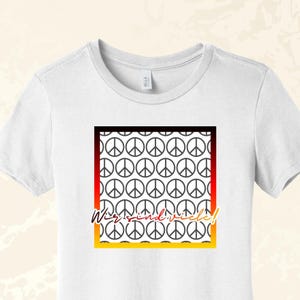 Könnte beinhalten: Ein weißes T-Shirt mit kurzen Ärmeln und einem quadratischen Aufdruck, der ein wiederkehrendes schwarzes Friedenszeichen-Muster zeigt. Das Quadrat ist von einem schwarz-rot-goldenen Farbverlauf umrandet. Der Text "Wir sind viele!" steht in Schreibschrift.
