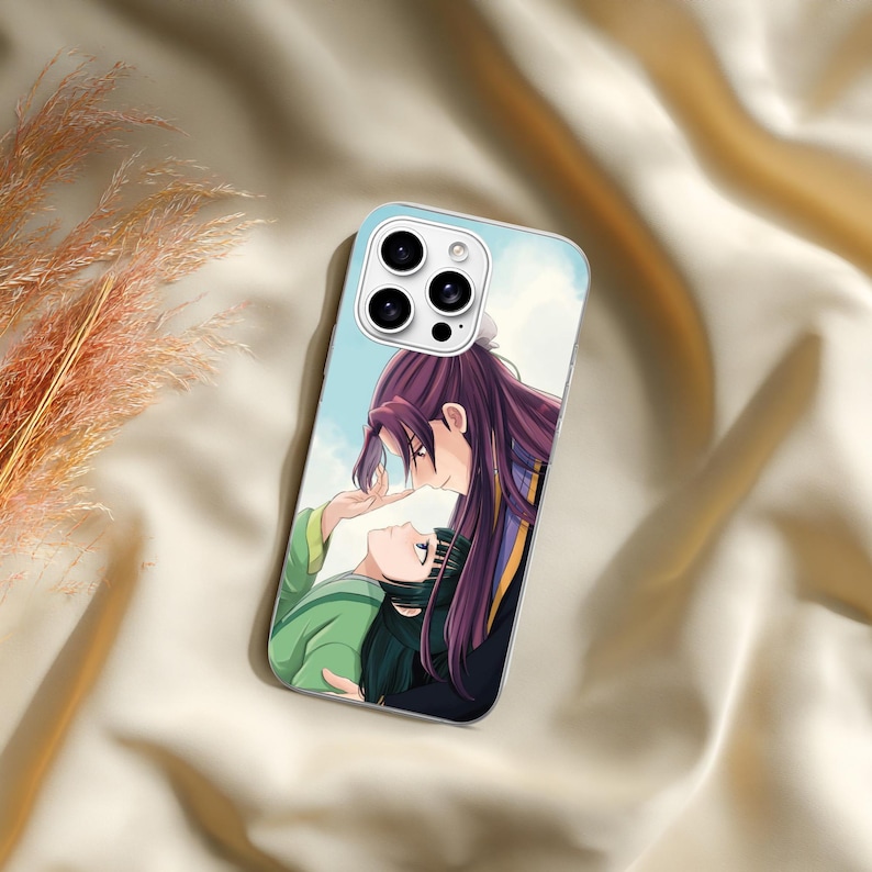 May include: A rectangular smartphone case featuring a printed anime-style illustration of two characters. One character has long dark purple hair and wears dark clothing, while the other has dark hair and wears a green garment. The background is light blue.
