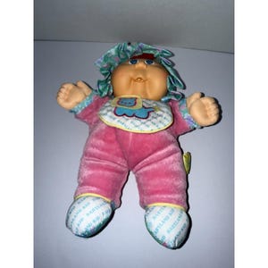 May include: A white ceramic mug with a black handle and the text "But First, Coffee" in a black, bold font. The mug is on a white surface.