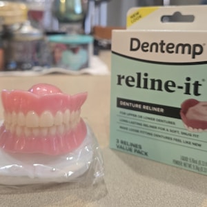 May include: A white ceramic mug with a black handle and the text "But First, Coffee" in a bold, black font. The mug is set against a neutral background, highlighting its simple design.