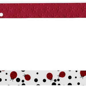 May include: A rectangular license plate frame featuring a two-tone design. The top section is a solid deep red with an embossed floral pattern. The bottom section is white with a scattered pattern of black polka dots and small red ladybugs.