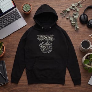 May include: A black hooded sweatshirt featuring a graphic print on the chest. The design includes the text "PANIC ROEL" in a stylized, jagged font above an illustration of a figure in a suit floating or falling, rendered in shades of gray.
