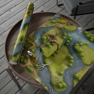 May include: A roll of landscape-themed wrapping paper and a wrapped gift with a brown ribbon sit on a wooden table. The paper features a map-like design with green trees, blue rivers, and yellow accents. Scissors and tape are also on the table.