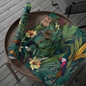 May include: A roll of wrapping paper and a wrapped gift with a brown ribbon sit on a wooden table. The paper features a vibrant tropical design with green leaves, yellow flowers, and a toucan. Scissors are placed on the paper.