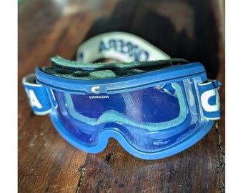 Occhiali da sci vintage anni '90 Carrera Everclear con montatura blu e cinturino regolabile, stile retrò invernale.