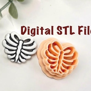 Könnte beinhalten: Zwei herzförmige Objekte, eines weiß und schwarz, das andere pfirsichfarben, die Rippenknäfigen ähneln. Der Text "Digital STL File" ist in Braun dargestellt. Die Objekte sind wahrscheinlich 3D-Modelle oder Designs für Kunsthandwerk oder digitale Kunst.